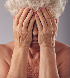 Elderly woman covering her face with hands