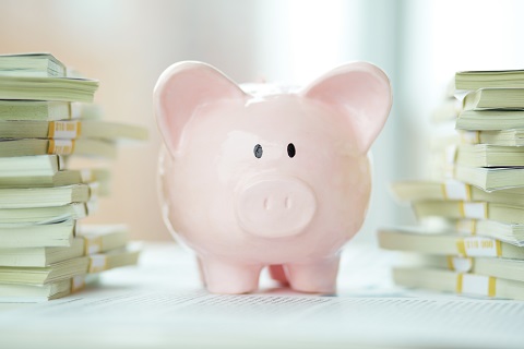 Piggy bank with stacks of money - care fees saved by Clarity Care Consulting being successful with CHC application