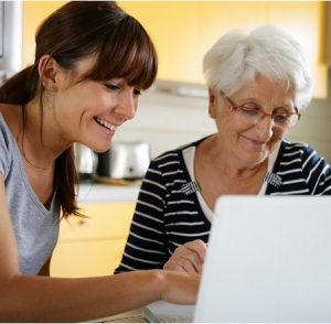 A younger woman and an elderly woman looking at a laptop for Care Funding Advice